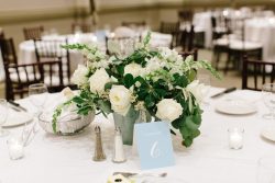 wedding centerpiece in white and green in a pale blue vase